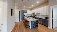 Located on N Liberty St in Spartanburg, South Carolina, this single-floor residence offers a thoughtfully designed layout that balances contemporary style with everyday functionality. The open-concept kitchen serves as a central highlight, featuring two-tone cabinetry — white uppers paired with slate-gray lowers — granite countertops, a subway tile backsplash, stainless steel appliances, and a central island with built-in shelving and bar seating. Light wood-tone flooring anchors the kitchen and flows into adjacent living areas.

The living room is bright and inviting, with multiple windows fitted with white blinds that allow natural light to fill the space. Recessed lighting and a ceiling fan add to the room's comfort and practicality.

The primary bedroom is generously proportioned, featuring soft carpet, multiple windows, and an en-suite bathroom with a dual-sink vanity topped in granite, light wood-tone flooring, and direct access to a walk-in closet. A secondary bedroom offers carpeted floors and natural light, while an additional room with a hallway entry provides flexible use. A second full bathroom includes a granite-topped vanity and a tiled shower-tub combination. A hallway lined with louver-door storage connects the spaces cohesively.