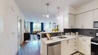 Located at 6670 Emergent Way in San Jose, CA, this well-appointed one-bedroom, one-bathroom residence offers a thoughtfully designed open-concept layout. The kitchen is a standout feature, showcasing crisp white cabinetry, quartz countertops, a bold black subway tile backsplash, stainless steel appliances including a gas range, microwave, dishwasher, and refrigerator, and a peninsula with pendant lighting that flows seamlessly into the dining and living areas. The living room is bright and welcoming, with large windows dressed in rich navy drapes that frame outdoor views and fill the space with natural light. Wood-style flooring runs throughout the main living areas, adding warmth and continuity. The spacious bedroom features plush carpet, a textured accent wall, a ceiling fan, and direct access to a walk-in closet. An arched hallway leads to the full bathroom, which is finished with large-format tile flooring and a full soaking tub surrounded by taupe subway tile. The unit also includes a private balcony, providing an outdoor retreat. Clean lines, modern fixtures, and a cohesive neutral palette with bold accent tones give this residence a polished, contemporary character throughout.