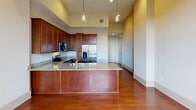 Located on Canal Street in the heart of New Orleans, this one-bedroom, one-bathroom residence offers a well-designed layout with upscale finishes throughout. Rich hardwood flooring flows seamlessly across the entire living space, complementing the soaring ceilings and recessed lighting that create a bright, open atmosphere.

The kitchen serves as a central focal point, featuring a large island with granite countertops, rich cherry wood cabinetry, and a full suite of stainless steel appliances, including a refrigerator with ice maker, electric range, built-in microwave, and dishwasher. Elegant pendant lights hang above the island, adding a refined touch to the space.

The generously sized bedroom benefits from large grid-pane windows on two walls, flooding the room with natural light and offering expansive views of the New Orleans skyline and surrounding cityscape. A ceiling fan adds comfort, while the polished hardwood floors continue throughout.

The bathroom is finished with tile flooring, a granite-topped vanity with white cabinetry, a tiled tub-shower combination, and stylish pendant lighting. A dedicated laundry room with in-unit washer hookups and built-in shelving provides added convenience. A separate closet completes this thoughtfully appointed urban residence.
