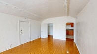 Located at 475 S New Hampshire Ave in the Koreatown neighborhood of Los Angeles, this 3-bedroom, 1-bathroom unit offers a compact yet functional single-floor layout. Warm-toned hardwood flooring runs throughout the main living areas and bedrooms, lending a cohesive and inviting feel to the space. The primary living area is a standout, featuring elegant ornate crown molding along the ceiling line that adds a classic architectural charm, along with a large window that allows natural light to fill the room. The primary bedroom is notably spacious, with two windows offering natural light and views of surrounding greenery. Additional bedrooms are finished with the same hardwood floors and clean white walls, providing versatile spaces. A dedicated closet area includes built-in storage cabinetry with a wall sconce. The kitchen features warm wood cabinetry, granite-style countertops, tile flooring, and a window, and is equipped with a gas range and refrigerator. The bathroom is finished with tile flooring and wainscoting, a shower-tub combination, and a window that brings in natural light. A connecting hallway ties the rooms together efficiently, completing this well-structured urban residence.