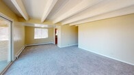 This single-floor, 2-bedroom, 2-bathroom unit is defined by its distinctive exposed ceiling beams and textured ceilings, which add architectural character throughout the living spaces. Warm yellow-toned walls and plush carpeting create a cohesive and comfortable atmosphere across the main living area and bedrooms.

The spacious living room benefits from multiple windows and a large sliding glass door that opens to a balcony with open outdoor views, filling the space with natural light. Baseboard heating runs throughout the unit, providing efficient warmth. A second sliding door in the primary bedroom also offers direct balcony access, complemented by a ceiling fan for added comfort.

The galley-style kitchen is efficiently designed with warm wood cabinetry, granite-look countertops, tile flooring, and a full suite of appliances including a gas range, dishwasher, and refrigerator. A dedicated doorway connects the kitchen to the rest of the unit seamlessly.

Both bathrooms feature tile flooring, wood-framed vanities with granite-look countertops, and natural light from windows. The full bathroom includes a tub-shower combination with tiled surround. The second bedroom offers carpeting and a bright window, maintaining the unit's consistent, comfortable aesthetic.