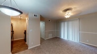 Located at 2039 Bent Creek Way SW in Atlanta, GA, this single-floor home offers a practical and comfortable layout with a neutral color palette throughout. The living area is generously sized, featuring plush wall-to-wall carpeting, a textured ceiling, and a stylish ceiling light fixture. Large sliding glass doors dressed with vertical blinds allow natural light to fill the space, creating a bright and open atmosphere. A chair rail detail runs along the walls, adding a subtle architectural touch. The kitchen is efficiently designed with white cabinetry, dark granite-style countertops, wood-look flooring, and a full suite of black appliances including a refrigerator, gas range, and dishwasher. Track lighting overhead provides ample task illumination. The bedrooms continue the carpeted flooring and are equipped with ceiling fans for comfort. The primary bedroom connects directly to a vanity area featuring white cabinetry and dark countertops, alongside a closet with bifold doors. The bathroom includes a tub-shower combination, wood-look tile flooring, and clean white fixtures. Throughout the home, consistent warm beige tones and practical finishes contribute to a cohesive and move-in ready environment.