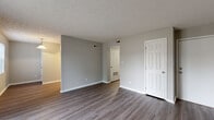 Located at 250 N East St in Plainfield, Indiana, this single-floor, 2-bedroom, 1-bathroom residence offers a practical and comfortable layout across a well-organized floor plan. The living room is a welcoming, open space featuring durable wood-look plank flooring, neutral gray walls, and a textured ceiling. A sliding glass door floods the room with natural light and provides direct access to a private outdoor deck, offering pleasant outdoor views. The living area flows into a combined dining and kitchen space, maintaining an efficient and connected feel throughout the common areas. Both bedrooms are carpeted and finished in muted gray tones, lending a calm, cozy atmosphere. The primary bedroom is a well-proportioned space with a closet and natural light from a window with blinds. The second bedroom similarly features carpeting and a window with outdoor views. Four closets are distributed throughout the home, providing ample storage. A hallway connects the main living spaces to the bedrooms and the full bathroom, which includes a tub/shower combo. Additional utility and laundry areas round out the functional amenities of this home. The consistent use of neutral tones and low-maintenance finishes throughout gives the residence a clean, move-in ready appeal.