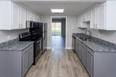 Located at 936 Mountain Creek Rd in Chattanooga, Tennessee, this two-floor residence offers a well-organized layout designed for comfortable everyday living. The main level features a bright living area finished with light wood-look flooring, neutral warm-toned walls, and a large sliding glass door dressed with vertical blinds that invites natural light and provides direct access to the outdoors. A staircase connects the two floors, with additional utility doors visible on the main level for added functionality. The kitchen is thoughtfully appointed with white upper cabinetry, gray lower cabinets, granite countertops, a stainless steel refrigerator, and a stainless electric range with over-the-range microwave. Light flooring carries through the kitchen, which connects openly to the living space. Upstairs, the carpeted bedrooms offer a quiet retreat, each featuring neutral beige walls and window blinds that allow natural light. The primary bedroom includes a built-in open closet with double hanging rods for ample storage. An additional carpeted bedroom with a single window provides a versatile space. The bathroom features light wood-look flooring, clean white fixtures, and a minimalist design. Throughout the home, a consistent neutral color palette and well-maintained finishes create a clean, move-in-ready atmosphere.
