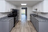 Located at 936 Mountain Creek Rd in Chattanooga, Tennessee, this two-floor residence offers a well-organized layout designed for comfortable everyday living. The main level features a bright living area finished with light wood-look flooring, neutral warm-toned walls, and a large sliding glass door dressed with vertical blinds that invites natural light and provides direct access to the outdoors. A staircase connects the two floors, with additional utility doors visible on the main level for added functionality. The kitchen is thoughtfully appointed with white upper cabinetry, gray lower cabinets, granite countertops, a stainless steel refrigerator, and a stainless electric range with over-the-range microwave. Light flooring carries through the kitchen, which connects openly to the living space. Upstairs, the carpeted bedrooms offer a quiet retreat, each featuring neutral beige walls and window blinds that allow natural light. The primary bedroom includes a built-in open closet with double hanging rods for ample storage. An additional carpeted bedroom with a single window provides a versatile space. The bathroom features light wood-look flooring, clean white fixtures, and a minimalist design. Throughout the home, a consistent neutral color palette and well-maintained finishes create a clean, move-in-ready atmosphere.
