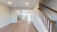 Located at 2744 Old Fort Pkwy in Murfreesboro, Tennessee, this two-story home offers a clean, modern aesthetic with thoughtfully selected finishes throughout. The main level features an open-concept layout where the living area flows seamlessly into the kitchen. The kitchen is a standout, showcasing white shaker-style cabinetry, granite countertops, a center island, subway tile backsplash, and a full suite of stainless steel appliances including a refrigerator with ice maker, range, microwave, and dishwasher. Light hardwood-style flooring runs throughout the main level, enhancing the bright and airy feel. A half bathroom on the main floor features a white vanity with clean fixtures. The staircase, accented with wood balusters and a warm handrail, leads to the upper level. Upstairs, the bedrooms are carpeted and receive generous natural light through large windows, with ceiling fans adding comfort. The upper-level bathrooms are well-appointed, with one featuring a soaking tub and shower combination and a granite-topped vanity, and another offering a walk-in shower. Neutral wall tones and recessed lighting throughout create a cohesive, move-in-ready atmosphere.
