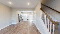 Located at 2744 Old Fort Pkwy in Murfreesboro, Tennessee, this two-story home offers a clean, modern aesthetic with thoughtfully selected finishes throughout. The main level features an open-concept layout where the living area flows seamlessly into the kitchen. The kitchen is a standout, showcasing white shaker-style cabinetry, granite countertops, a center island, subway tile backsplash, and a full suite of stainless steel appliances including a refrigerator with ice maker, range, microwave, and dishwasher. Light hardwood-style flooring runs throughout the main level, enhancing the bright and airy feel. A half bathroom on the main floor features a white vanity with clean fixtures. The staircase, accented with wood balusters and a warm handrail, leads to the upper level. Upstairs, the bedrooms are carpeted and receive generous natural light through large windows, with ceiling fans adding comfort. The upper-level bathrooms are well-appointed, with one featuring a soaking tub and shower combination and a granite-topped vanity, and another offering a walk-in shower. Neutral wall tones and recessed lighting throughout create a cohesive, move-in-ready atmosphere.