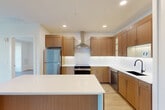 Located at 1801 N Beauregard St in Alexandria, Virginia, this well-appointed two-bedroom, two-bathroom residence offers a thoughtfully designed single-level layout. Light-toned hardwood-style flooring runs throughout the main living areas, complementing a clean, contemporary aesthetic defined by crisp white walls and recessed lighting.

The kitchen is a standout feature, showcasing warm wood-grain cabinetry, white quartz countertops, stainless steel appliances including a refrigerator, range with overhead hood, and dishwasher, as well as a matte black sink faucet and a tile backsplash. A kitchen island provides additional prep and counter space.

The combined living and dining area is bathed in natural light through large, black-framed windows that frame views of surrounding greenery. Both bedrooms continue the bright, airy feel, with the primary bedroom offering generous proportions and multiple windows with outdoor views. Four closets throughout the unit provide ample storage.

The two bathrooms are finished with modern fixtures, wood-toned vanities, and white countertops. One bathroom features a walk-in shower with full subway tile surround, a built-in niche, and mosaic tile flooring, while the second includes a tub-shower combination. An in-unit laundry area adds everyday convenience to this well-rounded residence.
