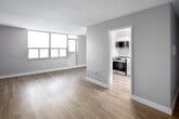 Located at 70 Park St E in Mississauga's Port Credit area, this single-floor suite offers a clean, contemporary aesthetic with consistent light-toned laminate flooring running throughout. The open living area benefits from large floor-to-ceiling windows that draw in generous natural light and provide views of the surrounding cityscape, creating a bright and airy atmosphere.

The kitchen is outfitted with sleek flat-panel white cabinetry extending to the ceiling, light stone countertops, a pale subway tile backsplash, and stainless steel appliances including a full-size refrigerator and dishwasher. The layout is efficient and well-organized, offering ample counter and storage space.

The bedrooms are well-proportioned, each featuring neutral grey walls, laminate flooring, and sliding-door closets with built-in hanging rails. Natural light reaches each room through dedicated windows. The bathroom presents a refined, minimalist design with a white stone-topped vanity, chrome fixtures, a frameless mirror with overhead lighting, and clean white finishes throughout.

Overall, the suite maintains a cohesive, modern palette of whites and soft greys, delivering a calm and functional living environment.