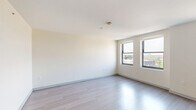 Located on the 9th floor at 2701 Park Ave in Detroit's vibrant Midtown neighborhood, this efficiently designed studio offers a well-planned single-floor layout encompassing a living area, kitchen, and full bathroom. The open living space is bathed in natural light from large windows that frame views of the surrounding Detroit cityscape, with clean white walls and light-toned luxury vinyl plank flooring throughout that enhance the sense of openness. The kitchen is thoughtfully appointed with warm wood lower cabinetry, sleek charcoal upper cabinets, a white subway tile backsplash, stainless steel appliances including a full-size refrigerator, dishwasher, and microwave, plus a dedicated closet space nearby for additional storage. The bathroom stands out with its eye-catching hexagonal patterned tile floor in a contrasting dark and white palette, complemented by white panel doors and a clean, modern vanity. A washer-dryer unit is also conveniently integrated into the layout. The overall aesthetic is modern and neutral, offering a bright, move-in-ready environment well-suited for those seeking a functional urban living space in the heart of Detroit.
