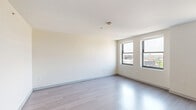 Located on the 9th floor at 2701 Park Ave in Detroit's vibrant Midtown neighborhood, this efficiently designed studio offers a well-planned single-floor layout encompassing a living area, kitchen, and full bathroom. The open living space is bathed in natural light from large windows that frame views of the surrounding Detroit cityscape, with clean white walls and light-toned luxury vinyl plank flooring throughout that enhance the sense of openness. The kitchen is thoughtfully appointed with warm wood lower cabinetry, sleek charcoal upper cabinets, a white subway tile backsplash, stainless steel appliances including a full-size refrigerator, dishwasher, and microwave, plus a dedicated closet space nearby for additional storage. The bathroom stands out with its eye-catching hexagonal patterned tile floor in a contrasting dark and white palette, complemented by white panel doors and a clean, modern vanity. A washer-dryer unit is also conveniently integrated into the layout. The overall aesthetic is modern and neutral, offering a bright, move-in-ready environment well-suited for those seeking a functional urban living space in the heart of Detroit.