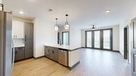 Located at 944 Broadcast Pl in Jacksonville, FL, this well-appointed 2-bedroom, 2-bathroom residence offers a thoughtfully designed open-concept layout. The combined living, dining, and kitchen area serves as the heart of the home, highlighted by light wood-style flooring, a ceiling fan, and expansive glass French doors that flood the space with natural light and provide access to an outdoor balcony area with open views.

The kitchen is a standout feature, boasting two-tone cabinetry with gray lower cabinets and white upper cabinets, a geometric tile backsplash, white quartz countertops, stainless steel appliances, and a central island with pendant lighting and an integrated dishwasher — ideal for both cooking and entertaining.

Both bedrooms are carpeted and feature ceiling fans, with the primary bedroom offering dual windows with scenic outdoor views and a spacious walk-in closet outfitted with built-in shelving and hanging systems. A second well-sized walk-in closet provides additional storage.

The primary bathroom impresses with a double-sink vanity featuring blue-gray cabinetry, black hardware, white countertops, and a glass-panel shower enclosure. Throughout the residence, dark gray door and window trim creates a modern, cohesive aesthetic against the crisp white walls.