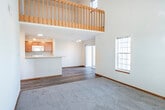 Located at 9117 Waterside St in Madison, WI, this two-bedroom, one-bathroom home spans two floors and offers a thoughtfully laid-out interior with a variety of appealing architectural details. The main floor features hardwood-style flooring throughout the kitchen and living areas, creating a warm and cohesive aesthetic. The kitchen is equipped with warm wood cabinetry, white appliances including a range and refrigerator, a sink, and track lighting overhead. A sliding glass door opens to a balcony, filling the space with natural light and providing outdoor access. The second floor is carpeted throughout and showcases soaring vaulted ceilings that lend an airy, open feel to the bedrooms and upper hallway. The generously sized primary bedroom benefits from large windows with transom detailing that frame scenic views of the surrounding landscape. A second bedroom features its own ceiling fan and vaulted ceiling. A dedicated closet with bi-fold doors and full-width hanging rod provides ample storage. The bathroom includes a full-size soaking tub with shower. A wood-railed staircase connects the two levels, adding a classic design touch. Natural light flows freely throughout, enhancing the overall brightness and welcoming ambiance of this well-appointed home.