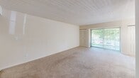 Located at 917 Cloister Road in Wilmington, Delaware, this one-bedroom, one-bathroom residence offers a well-organized single-floor layout designed for comfortable everyday living. The entrance leads into a spacious living area finished with neutral wall-to-wall carpeting and a textured ceiling, creating a clean and understated atmosphere. A sliding glass door with vertical blinds opens to an outdoor view, allowing natural light to fill the room and providing convenient exterior access. A chandelier-style light fixture adds a subtle decorative touch overhead. The kitchen features an L-shaped layout with warm wood-toned cabinetry, dark countertops, a white range, and a refrigerator, all complemented by tile flooring. A pass-through design connects the kitchen to the living space, supporting an open and functional flow. The generously sized bedroom is carpeted and bright, with a double-door closet, vertical blinds filtering outdoor light, and ample room for furnishings. A hallway connects the main areas and leads to the full bathroom, which is finished with tile flooring, a white vanity with cabinetry, an over-toilet storage unit, and a full soaking tub with a shower. The overall palette throughout is light and neutral, lending the space a clean, move-in-ready feel.