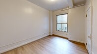 Located at 623 Southwest Park Avenue in Portland, Oregon, this two-bedroom, one-bathroom unit offers a thoughtfully arranged single-floor layout. Light wood flooring runs consistently throughout the space, creating a cohesive and clean aesthetic from room to room.

The entrance opens into a narrow hallway lined with white walls, crown molding, and natural light filtering in from a window at the far end. An intercom system is conveniently positioned near the entry. The kitchen features white cabinetry, under-cabinet lighting, a coil-top electric range, and a full-size refrigerator — all efficiently arranged in an L-shaped configuration that maximizes use of the available space.

Both bedrooms are bright and simply finished, with white walls accented by a chair-rail molding detail and windows fitted with blinds for light control. The primary bedroom includes a ceiling fan and wall-mounted heating unit. Exposed ceiling beams in one bedroom add a subtle architectural character to the space. Each bedroom benefits from its own closet for dedicated storage.

The bathroom is laid out in a galley style, featuring a single-sink vanity with a marble-style countertop, a full tub-shower combination, and a large mirror. The light wood flooring carries through here as well, maintaining the unit's consistent, clean design language throughout.