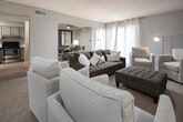 This two-floor residence offers a thoughtfully designed layout with a cohesive, contemporary aesthetic throughout. The living room is generously proportioned, featuring plush carpeting, sheer curtain-draped windows that invite natural light, and a media wall with a built-in fireplace flanked by coordinating artwork. The open flow connects seamlessly to the dining area, where a round wood table sits beneath a warm pendant light, accented by large framed mirrors that amplify the sense of space.

The kitchen is outfitted with gray cabinetry, stainless steel appliances including a range and dishwasher, granite-look countertops, and durable wood-look flooring — a functional and stylish space for everyday cooking.

Two bedrooms provide comfortable retreats. One features a bold dark wood headboard, soft neutral carpet, and layered white bedding, while the second offers a serene, light-filled atmosphere with balcony access, a ceiling fan, and a warm gold-toned color palette. Both rooms are well-lit with ample window coverage.

The bathrooms are clean and modern, with white vanities, well-lit mirrors, and a tiled tub-shower combination finished in marble-look tile. Wood-look flooring extends through the wet areas, tying the design together. The overall ambiance is elegant, neutral, and move-in ready.