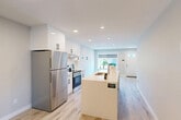Located in the established west Edmonton neighbourhood of Jasper Park, this two-storey home offers a thoughtfully designed layout spread across two floors. The main floor features an open-concept kitchen and living area finished with light hardwood-style flooring and recessed pot lighting. The kitchen is equipped with crisp white cabinetry accented by matte black hardware, quartz countertops, stainless steel appliances including a refrigerator and range, and a central island with an undermount sink — ideal for both cooking and entertaining. Large windows at the front of the main floor allow natural light to flow freely throughout the space.

The upper floor houses the primary bedroom, which includes a walk-in closet with wire shelving and direct access to a private ensuite bathroom. The ensuite features a sliding glass shower, white vanity with quartz countertop, and wood-look tile flooring. A second full bathroom of similar design serves the additional bedrooms.

The lower level provides two additional bedrooms with light-toned walls, light hardwood-style flooring, and egress windows that bring in natural light. A dedicated in-suite laundry room with a stacked washer and dryer adds everyday convenience. Two staircases connect the home's levels, and two closets provide ample storage throughout.