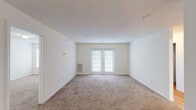 This single-floor residence offers a clean, functional layout designed for comfortable everyday living. The living area is generously sized, finished with neutral-toned wall-to-wall carpeting, a textured ceiling, and French doors that invite natural light and provide outdoor access. An open pass-through connects the living space to the kitchen, which is outfitted with rich dark wood cabinetry, granite-look countertops, a full suite of appliances including an electric range and microwave, and hardwood-style flooring that adds warmth to the space.

The bedrooms are well-proportioned, each featuring plush carpeting and windows with blinds that allow for ample natural light and pleasant outdoor views. The primary bedroom is complemented by a spacious walk-in closet equipped with multi-level wire shelving, offering excellent organizational capacity.

Both bathrooms are finished consistently with hardwood-style flooring, dark wood vanities with granite-look countertops, and full tub-shower combinations with chrome fixtures. A dedicated in-unit laundry area with a washer and additional shelving adds everyday convenience. Throughout the residence, neutral tones, white trim, and a light, airy palette create a cohesive and inviting atmosphere.