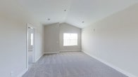 This single-story residence in Blossom Phase II offers three bedrooms and two bathrooms, designed with clean lines and a neutral palette that creates a bright, welcoming atmosphere. The home's standout architectural feature is its vaulted ceiling, which dramatically increases the sense of vertical space and airiness in the main living areas. Soft, greige-toned walls complement the plush wall-to-wall carpeting underfoot, lending warmth and comfort to the interior. Natural light filters in through well-placed windows, enhancing the open feel of the rooms. The crisp white ceiling and coordinating white trim provide a polished contrast to the warm neutral walls, contributing to a cohesive and move-in-ready aesthetic. Recessed lighting is installed throughout, offering versatile illumination options. The thoughtful layout across a single floor ensures easy accessibility and flow between spaces. Overall, the home presents a modern yet understated design, making it a practical and comfortable living environment suited for a variety of lifestyles.