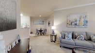 Located at 1010 Versant Dr in Brandon, Florida, this single-story residence offers a well-designed layout with comfortable living spaces throughout. The open-concept living and dining area is finished with soft carpet, crown molding, and neutral walls that create a warm, inviting atmosphere. A built-in arched shelving unit with dedicated media space serves as a focal point in the living room, while the adjacent dining area accommodates a round glass-top table beneath decorative wall art. The galley-style kitchen features light cabinetry, a double sink, tile flooring, and white appliances including a refrigerator, range, microwave, and dishwasher. Two well-proportioned bedrooms offer plush carpet, ceiling fans, and natural light from windows dressed with sheer curtains. The full bathroom is thoughtfully appointed with a wide vanity, tile flooring, a large mirror with overhead lighting, and a shower-tub combination. A dedicated in-unit laundry closet houses a full-size washer and dryer with overhead shelving for added storage. Throughout the residence, a cohesive neutral palette and consistent finishes contribute to a clean, comfortable living environment.