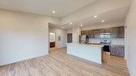 Located at 1220 W Highland Blvd in Lincoln, Nebraska, this well-designed 2-bedroom, 2-bathroom single-floor residence offers a clean, modern aesthetic throughout. The open-concept living area flows seamlessly into the kitchen, which is appointed with rich dark wood cabinetry, stainless steel appliances including a refrigerator, range, and microwave, and a generous island featuring a light quartz countertop and an undermount sink. Recessed lighting and light-toned luxury vinyl plank flooring enhance the bright, airy atmosphere of the main living space. A sliding glass door leads to a private balcony, providing pleasant outdoor views of the surrounding landscape. Both bedrooms are carpeted and feature ceiling fans and large windows that bring in natural light and offer open views. The primary bedroom is a comfortable, well-proportioned retreat with multiple windows. The two bathrooms are finished with wood-toned vanities, marble-style countertops, and light flooring. A dedicated laundry area includes a full-size washer and dryer. Two closets provide ample storage throughout the home. The overall design is cohesive and contemporary, making this a functional and attractive residence.