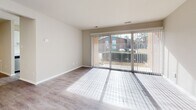Located at 7000 Coachman Lane in Henrico, Virginia, this single-floor unit offers a thoughtfully updated interior with a clean, neutral aesthetic throughout. The open living area is bathed in natural light, courtesy of large sliding glass doors fitted with vertical blinds that provide views of the surrounding landscape. Light-toned hard surface flooring runs through the main living spaces, lending a cohesive and modern feel.

The kitchen has been renovated to include white shaker-style cabinetry with matte black hardware, white quartz countertops, a subway tile backsplash, and a full suite of stainless steel appliances including a gas range, over-the-range microwave, and dishwasher. A hallway connects the kitchen to the rest of the unit seamlessly.

The bedrooms feature plush carpeting and ample natural light from well-positioned windows. One bedroom includes a ceiling fan and hard surface flooring, while another notably features built-in shelving and an in-unit washer, adding practical convenience. The bathroom is finished with a white vanity, quartz countertop, undermount sink, and matte black fixtures, complemented by wood-look flooring. The overall ambiance is bright, clean, and move-in ready.