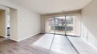 Located at 7000 Coachman Lane in Henrico, Virginia, this single-floor unit offers a thoughtfully updated interior with a clean, neutral aesthetic throughout. The open living area is bathed in natural light, courtesy of large sliding glass doors fitted with vertical blinds that provide views of the surrounding landscape. Light-toned hard surface flooring runs through the main living spaces, lending a cohesive and modern feel.

The kitchen has been renovated to include white shaker-style cabinetry with matte black hardware, white quartz countertops, a subway tile backsplash, and a full suite of stainless steel appliances including a gas range, over-the-range microwave, and dishwasher. A hallway connects the kitchen to the rest of the unit seamlessly.

The bedrooms feature plush carpeting and ample natural light from well-positioned windows. One bedroom includes a ceiling fan and hard surface flooring, while another notably features built-in shelving and an in-unit washer, adding practical convenience. The bathroom is finished with a white vanity, quartz countertop, undermount sink, and matte black fixtures, complemented by wood-look flooring. The overall ambiance is bright, clean, and move-in ready.