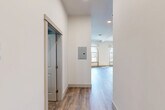 Located at 41 Fricker St in Providence, Rhode Island, this one-bedroom, one-bathroom unit blends historic architectural character with modern finishes across a single floor. The open living area is bathed in natural light from striking arched windows, highlighting the warm hardwood-style flooring that extends throughout the space. A decorative fireplace mantel with ornate carved detailing serves as a standout architectural focal point, adding classic charm to the otherwise clean, contemporary interior. The kitchen is well-appointed with light wood Shaker-style cabinetry, white subway tile backsplash, light countertops, and a full suite of stainless steel appliances including a refrigerator, range, microwave, and dishwasher. Recessed lighting and exposed ceiling beams add depth and character to the kitchen area. The bathroom features a modern wood-toned vanity with an undermount sink, a glass-enclosed shower, and wood-look tile flooring, creating a sleek and functional space. A dedicated utility room and closet provide practical storage solutions. The hallway includes an electrical panel neatly recessed into the wall. Throughout the unit, crisp white walls, recessed lighting, and consistent flooring create a cohesive, move-in-ready aesthetic that balances historic Providence character with contemporary convenience.
