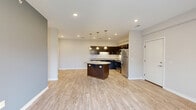 Located at 220 Marshall St in Monaca, PA, this single-floor residence offers three bedrooms and two bathrooms within a thoughtfully designed layout. The open-concept kitchen and living area serves as the heart of the home, featuring light wood-look luxury vinyl flooring, recessed lighting, and a striking octagonal granite-topped island beneath elegant pendant lights. Dark espresso cabinetry with granite countertops lines the kitchen walls, complemented by a full suite of stainless steel appliances. A set of French doors floods the living area with natural light and provides outdoor access, while a bold slate-blue accent wall adds a contemporary touch to the space. Both bathrooms are finished consistently with dark vanity cabinetry, granite countertops, large mirrors, and light wood-look flooring. Grab bars are thoughtfully incorporated, adding accessibility to the design. The three bedrooms are carpeted in a warm neutral tone and feature soft, neutral-painted walls. Two of the bedrooms include windows with views of the surrounding greenery and neighborhood, allowing natural light to brighten each room. Clean white panel doors and crisp white baseboards throughout tie the interior together with a cohesive, modern aesthetic.