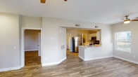 This single-floor residence offers a thoughtfully designed open layout with consistent wood-style flooring running throughout every room, creating a cohesive and warm aesthetic. The spacious living area is anchored by a ceiling fan and features large arched and rectangular windows that flood the space with natural light, along with a glass panel door providing direct access to an outdoor area. A second ceiling fan extends the open-concept space seamlessly into a casual lounge or dining zone.

The kitchen is a standout feature, equipped with stainless steel appliances including a refrigerator, electric range, and over-the-range microwave. Crisp white cabinetry pairs with a light countertop and a grey subway tile backsplash for a clean, modern finish. A peninsula with an integrated sink and bar-style overhang adds both functionality and an informal gathering space, open to the living areas.

The bedrooms are generously sized, each with a ceiling fan, neutral warm-toned walls, and ample natural light. One bedroom includes a private en-suite bathroom, while an additional full bathroom features a tub/shower combination, a wide vanity with white cabinetry, and matching wood-style flooring. Throughout, the design is clean and neutral, offering a versatile, move-in ready environment.