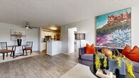 This single-floor residence offers a well-organized layout that balances open communal spaces with private retreats. The living room serves as the central gathering area, featuring wood-look flooring, a textured ceiling, and a large window that invites natural light and outdoor views. The space flows naturally into a dedicated dining area, providing a functional transition between relaxing and entertaining zones.

The kitchen is designed in a galley configuration, outfitted with white cabinetry, light countertops, and a full suite of stainless steel appliances, including a range, microwave, and refrigerator. A peninsula counter separates the kitchen from the main living space, adding both visual definition and additional prep area.

The unit includes two bedrooms, each with wood-look flooring and textured ceilings. The primary bedroom benefits from natural light through a window with outdoor views. A second bedroom features a stacked washer and dryer unit, providing in-unit laundry convenience. Two bathrooms serve the residence; one is a longer, corridor-style bath with a tub/shower combination and a white vanity, while the second is a compact full bath with a window, white cabinetry, and ample counter space. Neutral gray tones carry throughout, creating a cohesive and understated aesthetic.