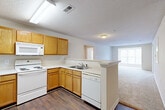 Located at 5402 Friendly Manor Dr in Greensboro, NC, this single-floor, three-bedroom, two-bathroom home offers a practical and comfortable layout. The open-concept kitchen flows directly into the living and dining areas, creating a connected and functional common space. The kitchen is equipped with warm honey-toned oak cabinetry, light countertops, wood-look flooring, and white appliances including a range, over-the-range microwave, dishwasher, and refrigerator. A peninsula counter separates the kitchen from the carpeted living area, which features a ceiling fan with light fixture and a large window that brings in natural light and outdoor views. The bedrooms are carpeted and neutrally toned, providing versatile living spaces. The spacious primary bedroom includes its own closet. Both bathrooms feature tub/shower combinations with chrome fixtures and wood-look flooring. A dedicated laundry room and four closets throughout the home add to the overall storage and convenience. Textured ceilings and neutral wall tones are consistent throughout, giving the home a clean, cohesive aesthetic. The single-level layout ensures easy accessibility across all rooms.