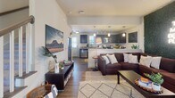 Located at 2415 Junction Boys Road in College Station, TX, this two-story home offers a well-designed layout that balances comfort and functionality. The main level features an open-concept living and kitchen area, where hardwood-style flooring flows seamlessly throughout. The living room is a standout space, anchored by a bold green moss accent wall with a neon sign, a ceiling fan, and large windows that invite natural light. A carpeted staircase with a classic wood newel post leads to the upper level.

The kitchen is outfitted with rich dark cabinetry, granite countertops, stainless steel appliances, a deep undermount sink, and pendant lighting, complemented by a casual dining area nearby. The open sightlines between the kitchen and living room create an inviting, connected atmosphere.

Bedrooms are found on both floors, each featuring plush carpeting and windows with blinds for natural light and privacy. The upper-level bedrooms are generously proportioned with closet access. Bathrooms include a full tub-shower combination with brushed nickel fixtures and granite vanity surfaces, offering clean, functional design.

Overall, this home presents a warm and contemporary aesthetic, with thoughtful details and versatile spaces well-suited for everyday living in the heart of College Station.