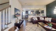 Located at 2415 Junction Boys Road in College Station, TX, this two-story home offers a well-designed layout that balances comfort and functionality. The main level features an open-concept living and kitchen area, where hardwood-style flooring flows seamlessly throughout. The living room is a standout space, anchored by a bold green moss accent wall with a neon sign, a ceiling fan, and large windows that invite natural light. A carpeted staircase with a classic wood newel post leads to the upper level.

The kitchen is outfitted with rich dark cabinetry, granite countertops, stainless steel appliances, a deep undermount sink, and pendant lighting, complemented by a casual dining area nearby. The open sightlines between the kitchen and living room create an inviting, connected atmosphere.

Bedrooms are found on both floors, each featuring plush carpeting and windows with blinds for natural light and privacy. The upper-level bedrooms are generously proportioned with closet access. Bathrooms include a full tub-shower combination with brushed nickel fixtures and granite vanity surfaces, offering clean, functional design.

Overall, this home presents a warm and contemporary aesthetic, with thoughtful details and versatile spaces well-suited for everyday living in the heart of College Station.