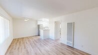 Located on Burbank Boulevard in the Tarzana neighborhood of Los Angeles, this well-appointed single-floor unit offers a clean, modern aesthetic defined by bright white walls and light wood-toned flooring that runs seamlessly throughout the space. The open-plan living, dining, and kitchen area forms the heart of the unit, creating a cohesive and functional layout. The kitchen is well-equipped with crisp white cabinetry extending to the ceiling for ample storage, a stainless steel refrigerator, a white range, a sink with under-counter storage, and a peninsula that provides additional counter space and naturally separates the kitchen from the living area. The living area receives natural light through a large window fitted with vertical blinds, offering views of the surrounding greenery, and includes a wall-mounted HVAC unit for year-round comfort. The bedroom is a comfortable, sun-lit room featuring a full-width mirrored sliding closet that enhances the sense of space. The bathroom is outfitted with a tub and shower combination enclosed by sliding glass doors, a toilet, and a vanity. A ceiling fan in the living area and dedicated entry door with thermostat controls complete this efficiently designed and move-in ready unit.