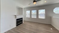 Located at 5880 Boulder Falls St in Henderson, NV, this single-floor home offers 1,010 square feet of thoughtfully designed living space across four bedrooms and two bathrooms. The open living room serves as the heart of the home, featuring a classic white-mantled fireplace with a built-in niche above, wood-look vinyl flooring, a ceiling fan with light, and multiple windows dressed with blinds that invite natural light and neighborhood views. The adjacent kitchen is well-appointed with dark cabinetry, light countertops, a gray subway tile backsplash, and stainless steel appliances including a gas range, microwave, and refrigerator, all illuminated by recessed lighting. The primary bedroom spans 190 square feet and includes dual sliding-door closets with wire shelving, offering ample storage. Additional bedrooms feature carpet flooring and windows with natural light. Both bathrooms are finished with dark vanity cabinets, light countertops, and wood-look vinyl flooring; one includes a tub/shower combo, while the other features a well-lit vanity mirror with a modern light fixture. The home's neutral gray and white palette throughout creates a clean, move-in-ready atmosphere.