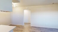 Located at 4004 S Manhattan Ave in Tampa, FL, this one-bedroom, one-bathroom unit offers a well-organized single-floor layout designed to maximize every square foot. The open-concept living, dining, and kitchen area forms the heart of the home, creating a seamless flow between daily living spaces. The kitchen is outfitted with crisp white shaker-style cabinetry with black hardware, light-toned countertops, a range, over-range microwave, and a full-size refrigerator. A track lighting fixture and windows allowing natural light make the kitchen feel bright and functional. Wood-look luxury vinyl plank flooring runs consistently throughout the unit, lending a clean and cohesive aesthetic. The living and dining area is open and airy, with neutral warm-toned walls and a ceiling-mounted multi-bulb light fixture. A hallway connects the main living area to the private bedroom, which features a ceiling fan with light, a window with blinds that invites natural light, and access to two closets for ample storage. The bathroom includes a full tub-shower combo with white tile surround and a frosted window for ventilation and privacy. The unit presents a clean, move-in ready interior throughout.