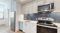 Located at 800 N 2nd St in Phoenix, AZ, this thoughtfully designed 3-bedroom, 1-bathroom unit offers a modern living experience across a single floor. Light wood-style flooring flows consistently throughout, creating a warm and cohesive aesthetic.

The kitchen is a standout feature, showcasing crisp white cabinetry extending to the ceiling, a bold navy herringbone tile backsplash, white quartz countertops, and a full suite of stainless steel appliances including a refrigerator, electric range, over-the-range microwave, and dishwasher.

The three bedrooms are bright and clean, finished with the same wood-style flooring and white walls. The primary bedroom features a built-in closet with shelving, while another bedroom benefits from corner wraparound windows that invite generous natural light and city views.

The bathroom is well-appointed with a tiled tub-shower surround in neutral tones, wood-style flooring, a white vanity with an illuminated mirror, and brushed nickel fixtures throughout.

A hallway connects the living spaces efficiently, and the open living area provides a versatile layout. The overall design is clean and contemporary, well-suited for urban living in the heart of Phoenix.