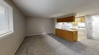 Located at 2720 S Emporia St in Wichita, KS, this one-bedroom, one-bathroom apartment offers a practical and efficient single-floor layout. The combined kitchen and living room serves as the heart of the unit, featuring plush wall-to-wall carpeting in the living area and a smooth tile floor in the kitchen zone. The kitchen is equipped with warm wood-toned cabinetry — both upper and lower — along with a white dishwasher, a double sink, and a refrigerator. A peninsula-style countertop separates the kitchen from the living space, creating an open-concept feel. Neutral-toned walls and a textured ceiling run throughout, lending a clean and cohesive look. Windows allow natural light to filter into both the living area and bedroom, keeping the space feeling bright and airy. The bedroom is a comfortable size, featuring soft carpet, two side-by-side closets offering ample storage, and a window with an outdoor view. The bathroom includes a full soaking tub with a showerhead, chrome fixtures, and an overhead wood-toned cabinet for storage. Overall, the unit presents a straightforward and functional design with a neutral palette throughout.