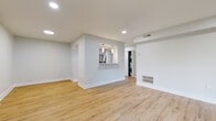 This thoughtfully renovated single-floor residence combines clean, contemporary design with practical functionality throughout. The open living area is anchored by light-toned hardwood flooring and crisp white walls, creating a bright and welcoming atmosphere. Recessed lighting throughout the main living space adds a polished touch, while a large sliding glass door floods the room with natural light and provides direct views of lush, mature greenery outside.

The kitchen features a pass-through window that opens to the living area, promoting an open and connected feel. Stainless steel appliances, including a full-size refrigerator and dishwasher, are complemented by white cabinetry and light countertops. A dedicated in-unit laundry area with a stacked washer and dryer adds everyday convenience.

The bedrooms are finished with plush neutral carpeting and ample closet space, offering a comfortable and quiet retreat. One bedroom benefits from a window with garden views, bringing in soft natural light.

The bathroom is a standout feature, showcasing a tub-shower combination wrapped in bold teal herringbone tile that provides a striking contrast to the clean white fixtures and light stone-look floor tile. The overall design of this residence balances modern aesthetics with comfortable, livable spaces.