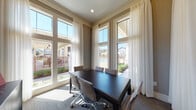 Located in College Station, Texas, this single-floor professional amenity space is designed to blend function with an upscale aesthetic. The layout includes a dedicated conference room and a private office area, each thoughtfully appointed to support productive work and meetings.

The conference room is a standout feature, boasting soaring ceilings and floor-to-ceiling windows dressed with sheer white drapery that flood the space with natural light. A sleek dark-wood conference table surrounded by modern ergonomic chairs anchors the room, while direct views of the outdoor pool and courtyard area create an inspiring and open atmosphere.

The adjacent private office mirrors the same elevated design sensibility, featuring rich crimson accent walls adorned with bold contemporary artwork, adding a striking visual contrast to the neutral tones throughout. A dark credenza provides functional storage, while tall windows continue the theme of generous natural light and outdoor connectivity.

Glass-paneled French doors with transom windows connect the two areas, maintaining visual openness between spaces while offering privacy when needed. The patterned carpet flooring, crown molding details, and carefully curated décor throughout lend the space a polished, professional character. Together, these rooms offer a well-equipped and visually refined environment ideal for collaboration and focused work.