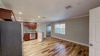 This thoughtfully designed single-floor residence offers a smart and functional layout across a compact yet comfortable footprint. The open-concept living and kitchen area is anchored by rich hardwood-style flooring and neutral gray walls, creating a bright and welcoming atmosphere enhanced by natural light from a large window.

The kitchen is a true standout, showcasing rich cherry wood cabinetry with crown molding, granite countertops, a mosaic tile backsplash, and a full suite of stainless steel appliances including a refrigerator, range, microwave, and dishwasher. A peninsula with a curved granite overhang provides additional prep space and casual seating, accented by modern pendant lighting overhead.

The bedroom is a comfortable retreat featuring soft carpeting, neutral tones, and a window with views of surrounding greenery. Three closets — including one with louvered doors — provide ample storage throughout the space.

The bathroom is finished with the same attention to detail, featuring a rich wood vanity with granite countertop, large-format tile flooring, and a shower-tub combination. Crown molding in the main living area adds an elegant architectural touch, while recessed lighting throughout ensures a well-lit, polished interior. This home combines practical design with quality finishes for comfortable everyday living.