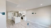 Located at 11131 110A Ave NW in Edmonton, Alberta, this well-designed two-storey home offers three bedrooms, three bathrooms, and thoughtfully organized living spaces across two floors. The main floor houses a contemporary kitchen appointed with crisp white cabinetry, quartz countertops, a central island with an undermount sink, stainless steel appliances, and recessed lighting — all complemented by light-toned vinyl plank flooring and zebra-shade windows that allow ample natural light. The upper floor features the spacious primary bedroom complete with a walk-in closet equipped with wire shelving systems, alongside additional bedrooms, each finished in neutral tones with access to closet storage. All three bathrooms maintain a clean, modern aesthetic with white vanities featuring quartz countertops, black hardware accents, glass-enclosed showers, and matching vinyl plank flooring. A central hallway and staircase connect both levels seamlessly. Throughout the home, a consistent neutral colour palette of soft greys and whites, paired with white trim and modern fixtures, creates a bright, cohesive, and move-in-ready living environment.