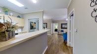 This single-story, two-bedroom, two-bathroom residence offers a thoughtfully organized layout across a compact yet efficient footprint. The open-concept living, dining, and kitchen area forms the heart of the home. The living room features crown molding, a tiled fireplace, ceiling fan, and large windows that admit generous natural light, creating a warm and inviting atmosphere. Adjacent to it, the dining area is distinguished by a soft blue accent wall, hardwood-style flooring, and a pendant light fixture overhead.

The galley-style kitchen is well-equipped, featuring light wood cabinetry, white appliances including a dishwasher, range, and refrigerator, ample counter space, and a breakfast bar that opens to the living area. A louvered pantry door provides additional storage.

The primary bedroom offers carpeted flooring, a large window, and direct access to its en-suite bathroom, which includes a soaking tub with shower combination. A spacious walk-in closet with built-in shelving serves the primary suite. The second bedroom is similarly comfortable, and the second full bathroom mirrors the first with a tub-shower combination and light wood vanity cabinetry. A hallway connects the private areas of the home seamlessly.
