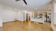 This single-floor residence showcases a thoughtfully designed, open-concept layout that seamlessly connects the living area to the kitchen. Light-toned hardwood-style flooring runs throughout, lending warmth and visual continuity across the space. Recessed lighting and a ceiling fan illuminate the main living area, which offers generous room for furniture arrangement.

The kitchen is a standout feature, equipped with light wood cabinetry accented by matte black hardware, a classic white subway tile backsplash, and granite countertops that extend across a peninsula ideal for casual dining or meal prep. Stainless steel appliances — including a range, microwave, and refrigerator — complete the well-appointed kitchen. A window above the counter area allows natural light to filter in.

The bedroom is a comfortable, well-lit space featuring multiple windows with blinds, a ceiling fan, and access to a private en-suite bathroom. The en-suite bath includes a granite-topped vanity with light wood cabinetry and a large mirror. A second bathroom offers a tub and shower combination with white tile surround.

A dedicated laundry room houses a full-size top-loading washer and dryer, adding everyday convenience. Throughout the unit, clean white walls and consistent finishes create a cohesive, modern aesthetic.