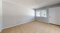 Located at 444 Florida St SE in Albuquerque, New Mexico, this efficient one-bedroom, one-bathroom home offers a well-organized single-floor layout. The living room features neutral gray walls, light tile flooring, and a large window fitted with blinds that allows generous natural light to fill the space, with views of the surrounding outdoor area. Adjacent to the living room, the kitchen is equipped with white cabinetry, granite-style countertops, a stainless steel refrigerator, and a range, complemented by a window above the sink that adds to the bright and functional atmosphere. The bedroom is a comfortable retreat with light wood-look laminate flooring, a window with outdoor views, and a sliding double-door closet offering practical storage. Ceiling vents ensure climate control throughout. The bathroom is clean and well-appointed, featuring a white vanity with a cultured marble countertop, a framed medicine cabinet mirror, brushed nickel fixtures, and tile flooring that ties the space together cohesively. Throughout the home, a consistent soft gray color palette, white trim, and textured ceilings create a clean, neutral aesthetic suited for a variety of interior styles.