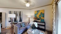 This single-story residence offers a thoughtfully designed interior with cohesive contemporary finishes across all rooms. The living area serves as a welcoming focal point, featuring a tray ceiling with an ornate pendant light fixture, crown molding, and warm-toned walls. A plush gray sofa, layered area rug, and a sleek console table beneath bold, colorful artwork create an inviting and curated atmosphere.

The kitchen is well-equipped with stainless steel appliances, including a refrigerator, range, and microwave. Light gray flat-panel cabinetry extends to the ceiling, providing generous storage, while granite countertops and a subway tile backsplash add a polished aesthetic. A kitchen island with a double undermount sink and matching granite surface offers additional workspace. Wood-look flooring runs throughout the kitchen, connecting seamlessly to adjoining areas.

The bedrooms are comfortably scaled, each featuring ceiling fans, natural light from windows with decorative curtains, and plush carpeting. The primary bedroom includes a walk-in closet with built-in shelving for organized storage.

The primary bathroom features a dual-sink vanity with granite countertops, gray cabinetry, a large mirror with overhead lighting, a glass-enclosed shower, and wood-look flooring, delivering a clean and functional design.