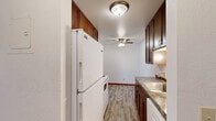 This 2-bedroom, 1-bathroom unit in Lauderdale, Minnesota offers a practical and comfortable single-floor layout. The living area is bright and open, featuring plush carpeting, a baseboard heating system, a wall-mounted air conditioning unit, and a sliding glass door that opens to a private balcony with views of surrounding greenery — bringing in ample natural light.

The galley-style kitchen is well-appointed with rich, dark wood cabinetry extending to the ceiling for generous storage, a tile backsplash, granite-toned countertops, wood-look tile flooring, and white appliances including a range and over-the-range microwave. A ceiling fan adds comfort to the adjoining dining area.

Both bedrooms are carpeted and finished with clean white walls and warm wood baseboards. Each room features a ceiling fan with light fixture, a baseboard heater, and a window framing leafy outdoor views. The primary bedroom offers a comfortable and well-proportioned space for rest and relaxation.

The bathroom is neatly finished with large-format neutral tile surrounding a soaking tub and shower combination, paired with a clean white sink. A hallway and dedicated closet round out this efficiently designed unit, making it a functional and inviting home.