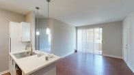 This single-floor residence offers a thoughtfully designed layout that balances comfort and functionality throughout. The open-concept living and kitchen area serves as the heart of the home, featuring warm hardwood-style flooring that extends seamlessly across the main living spaces. The kitchen is well-equipped with stainless steel appliances, including a refrigerator, range, and over-the-range microwave, complemented by white shaker-style cabinetry, light countertops, and a classic tile backsplash. A peninsula with pendant lighting provides additional workspace and connects the kitchen to the living area. The living space is bright and airy, with a sliding glass door fitted with vertical blinds that opens to an outdoor area, allowing natural light to pour in. The bedrooms offer plush carpeting underfoot, neutral gray walls, and ample natural light from well-placed windows, including a charming built-in window seat in one of the rooms. The bathrooms are clean and functional, featuring white vanities with updated fixtures, a tub-shower combination, and wood-style flooring. Throughout the residence, soft neutral tones and clean white trim create a cohesive, modern aesthetic that is both inviting and move-in ready.