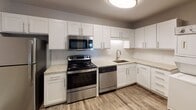 Located at 524 Bramlet Rd. in Charlotte, NC, this single-floor unit offers a thoughtfully updated interior with a cohesive modern aesthetic throughout. The living area makes a striking impression with a painted dark brick accent wall, hardwood-style flooring, and a ceiling fan, creating a comfortable and stylish setting. A sliding glass door brings in natural light and provides outdoor access.

The kitchen is well-appointed with crisp white shaker-style cabinetry, light granite countertops, a white subway tile backsplash, and a full suite of stainless steel appliances including a range, microwave, dishwasher, and refrigerator. The hardwood-style flooring continues seamlessly throughout the main living and kitchen areas.

Multiple bedrooms are carpeted and feature ceiling fans, natural light from windows with blinds, and generous closet space, including double closets in at least one bedroom. The neutral gray walls provide a versatile backdrop throughout.

The bathroom is finished with a gray vanity, granite countertop, large framed mirror, and a tub-shower combination with white subway tile surround. Wood-look flooring carries into the bathroom, tying the space together with a consistent, updated look.